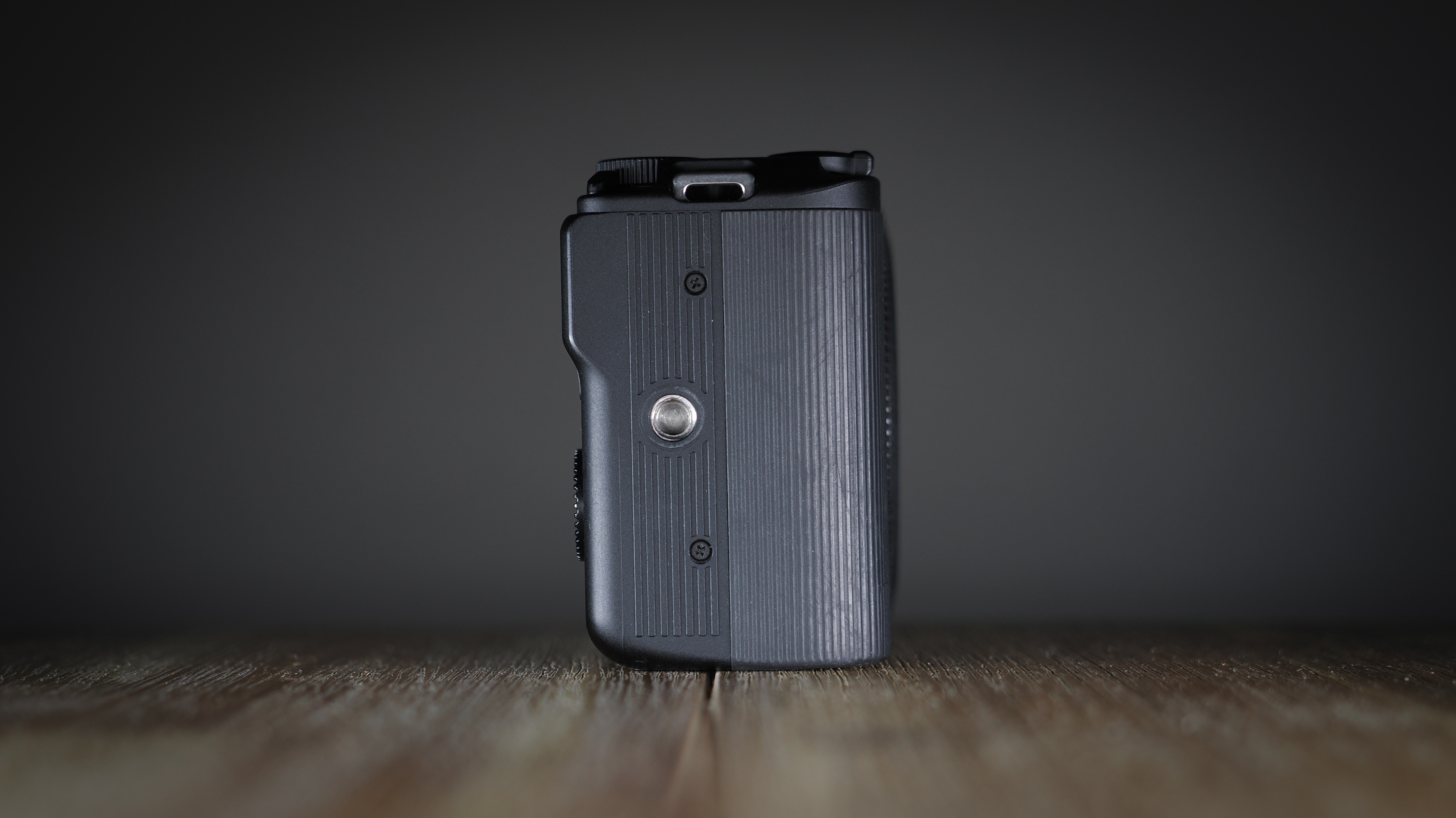 Canon EOS R50 V on a wooden surface, against a dark background