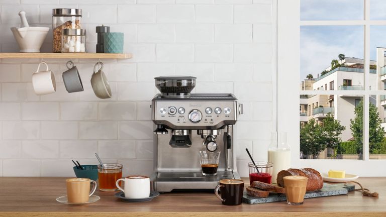 The Breville Barista Express espresso machine on a wooden worktop with white tiles and a window.