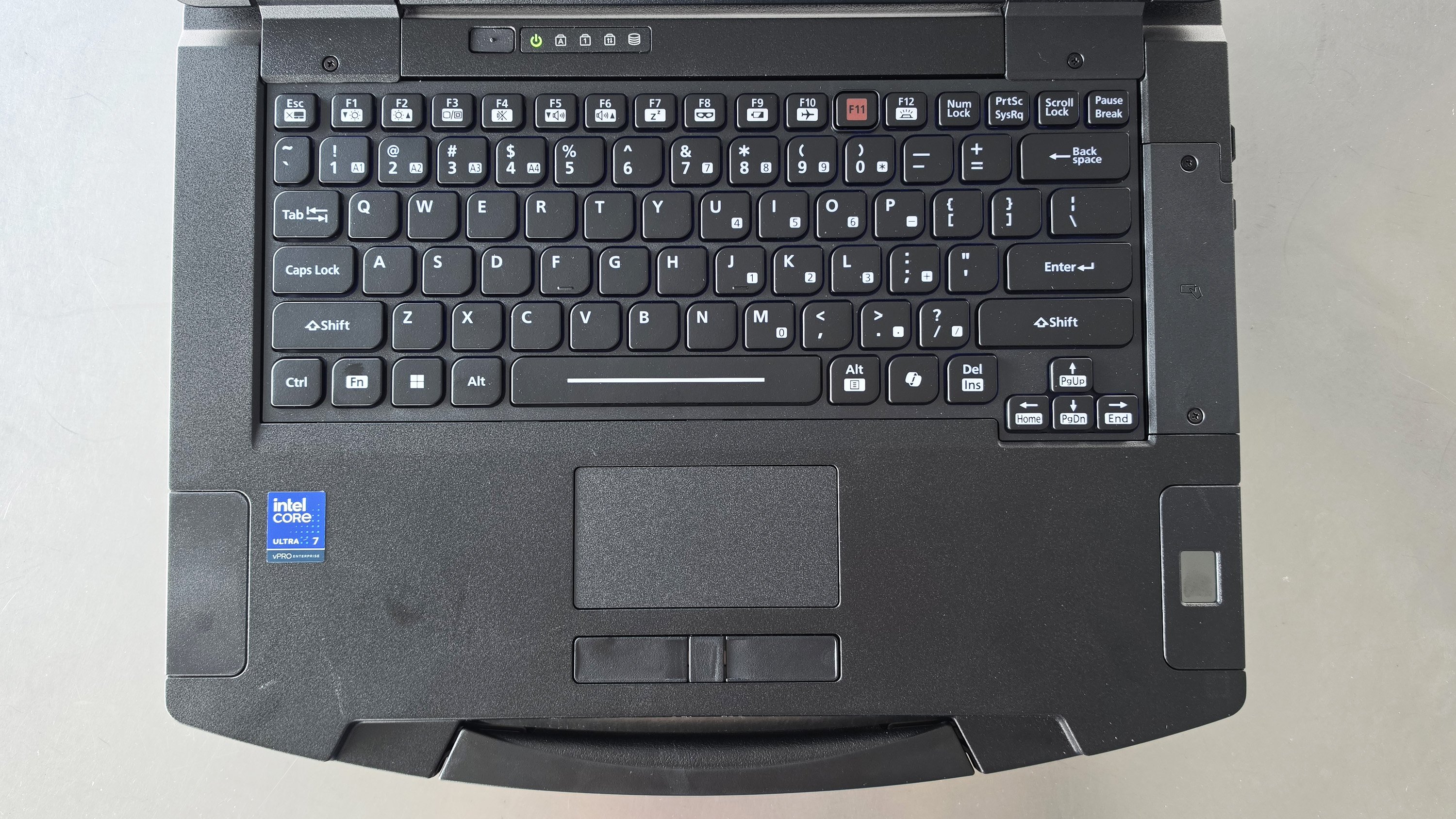 Black laptop viewed from above, showing a full keyboard and touchpad. Intel Core i7 sticker is visible on the left. Modern and functional design.