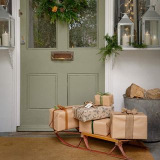 Green front door with wreath and presents on sleigh