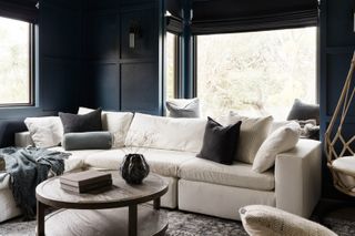 A living room with dark navy walls and a cream sofa