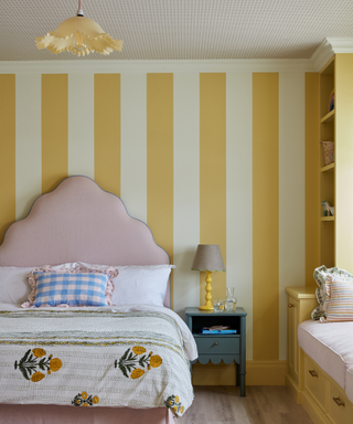 bedroom with yellow striped walls and pink headboard