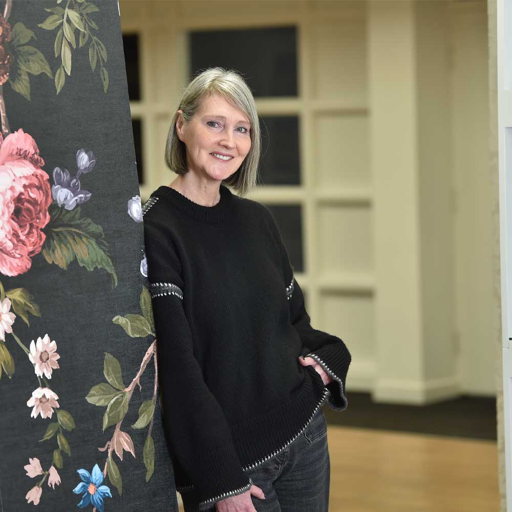 picture of Paula Taylor leaning against a wallpapered wall 