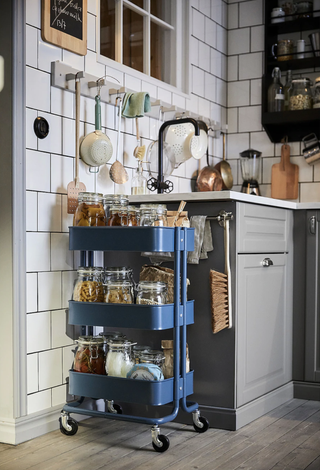 Blue Ikea Raskog trolley in kitchen containing glass food jars
