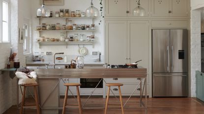 Bright and minimal white kitchen with long stainless steel counters and industrial metal open storage 