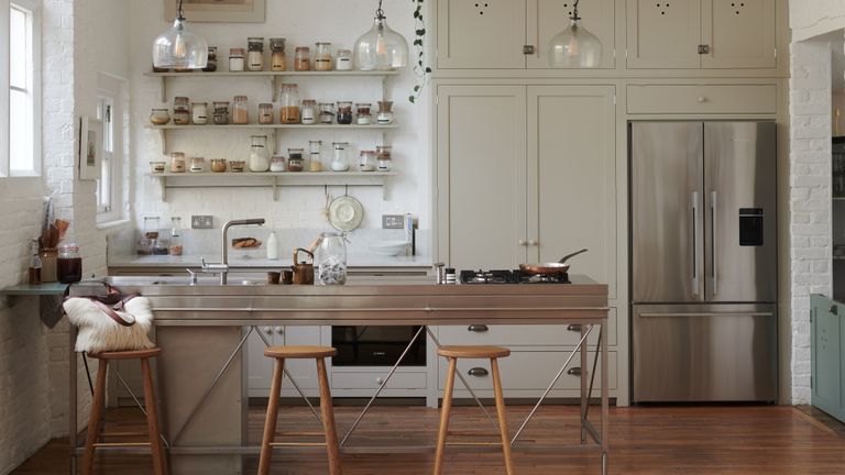 Bright and minimal white kitchen with long stainless steel counters and industrial metal open storage