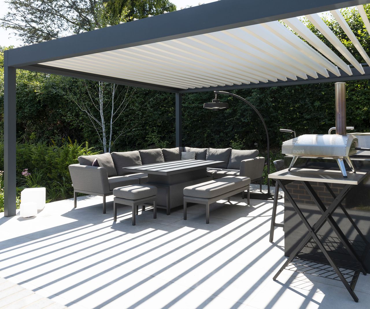 A covered patio seating area and outdoor kitchen with a louvred pergola canopy