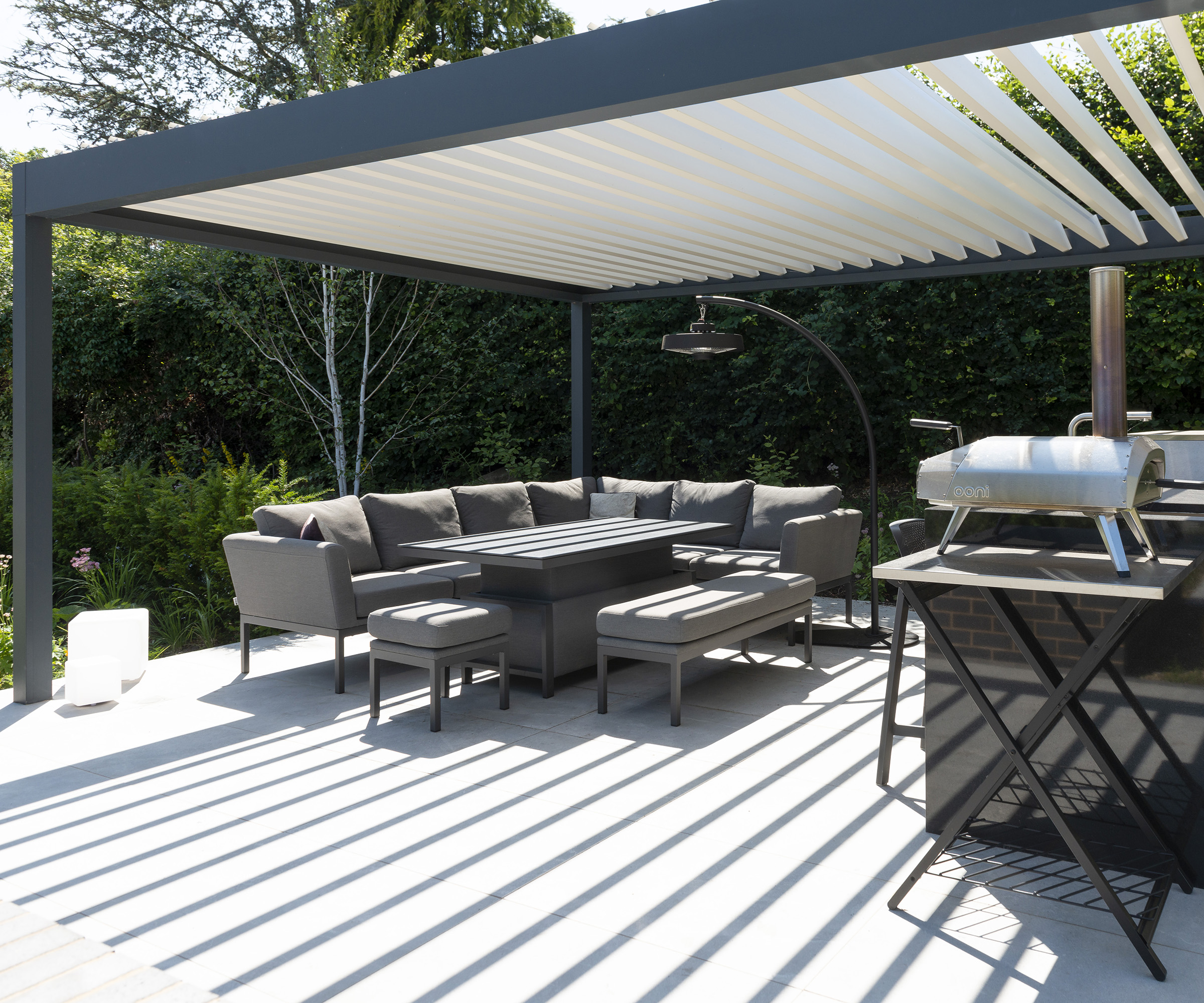 A covered patio seating area and outdoor kitchen with a louvred pergola canopy