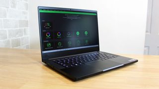 Image shows an open Razer Blade 14 laptop on a wooden table, turned on.