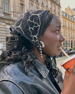 Fashion influencer Raïssa Tchoulague on the street in Europe wearing a chic fall outfit styled with a black headscarf.