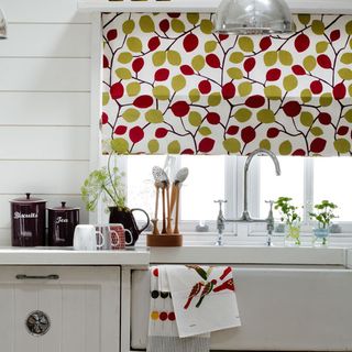 white kitchen with floral curtains and drawers