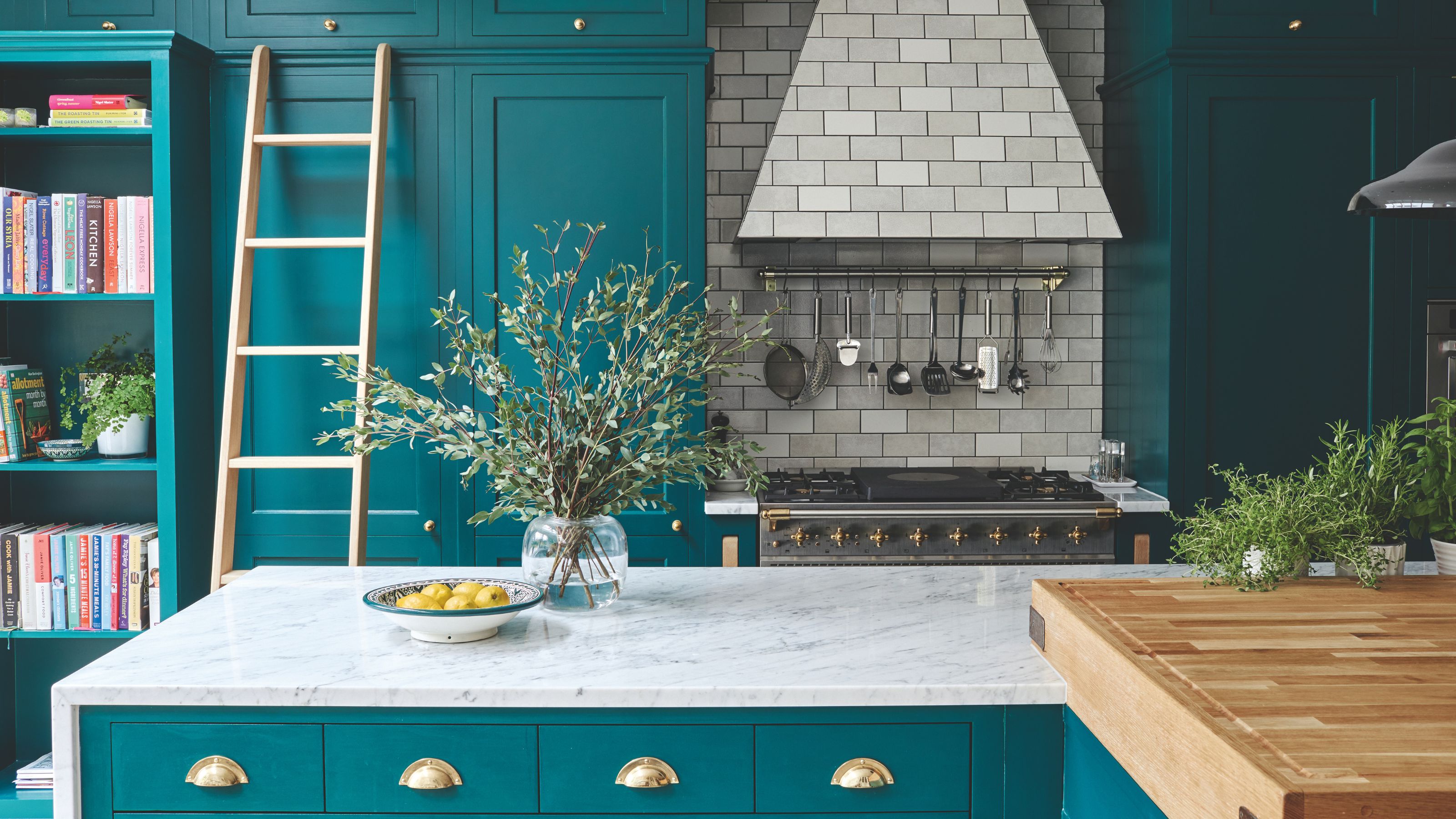 Kitchen with teal kitchen cabinets and white-grey marble countertop and grey tiled cooker hood