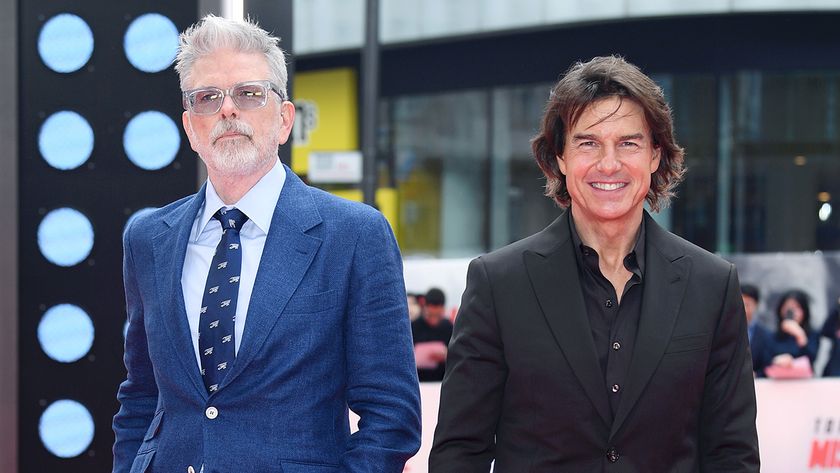 Tom Cruise and Christopher McQuarrie suit up (the actor in black and the director in blue) and stare at the camera at the Final Reckoning movie premiere. 