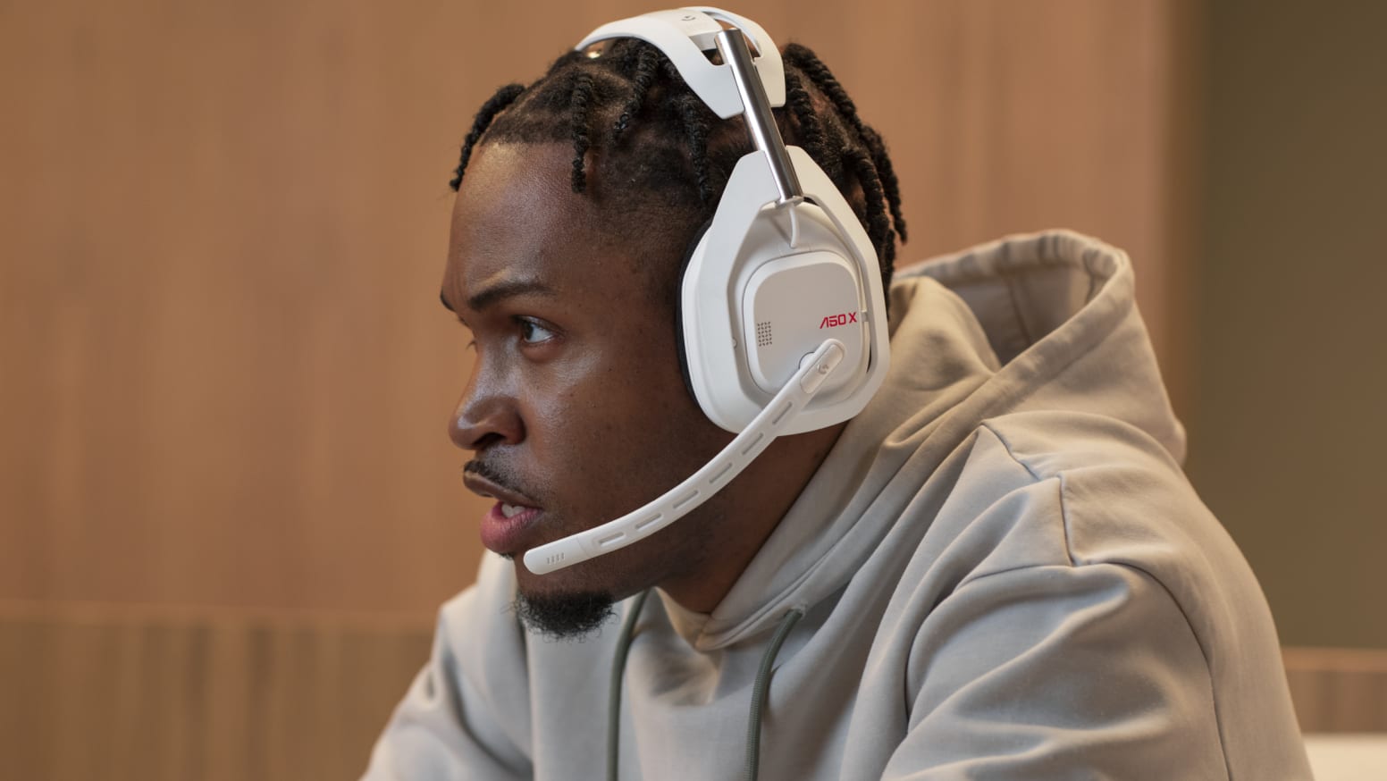 A sitting man wearing a white Logitech Astro A50 X Wireless headset.