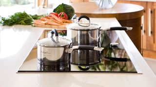 induction hob with stainless steel saucepans to support article on how to clean a glass stovetop