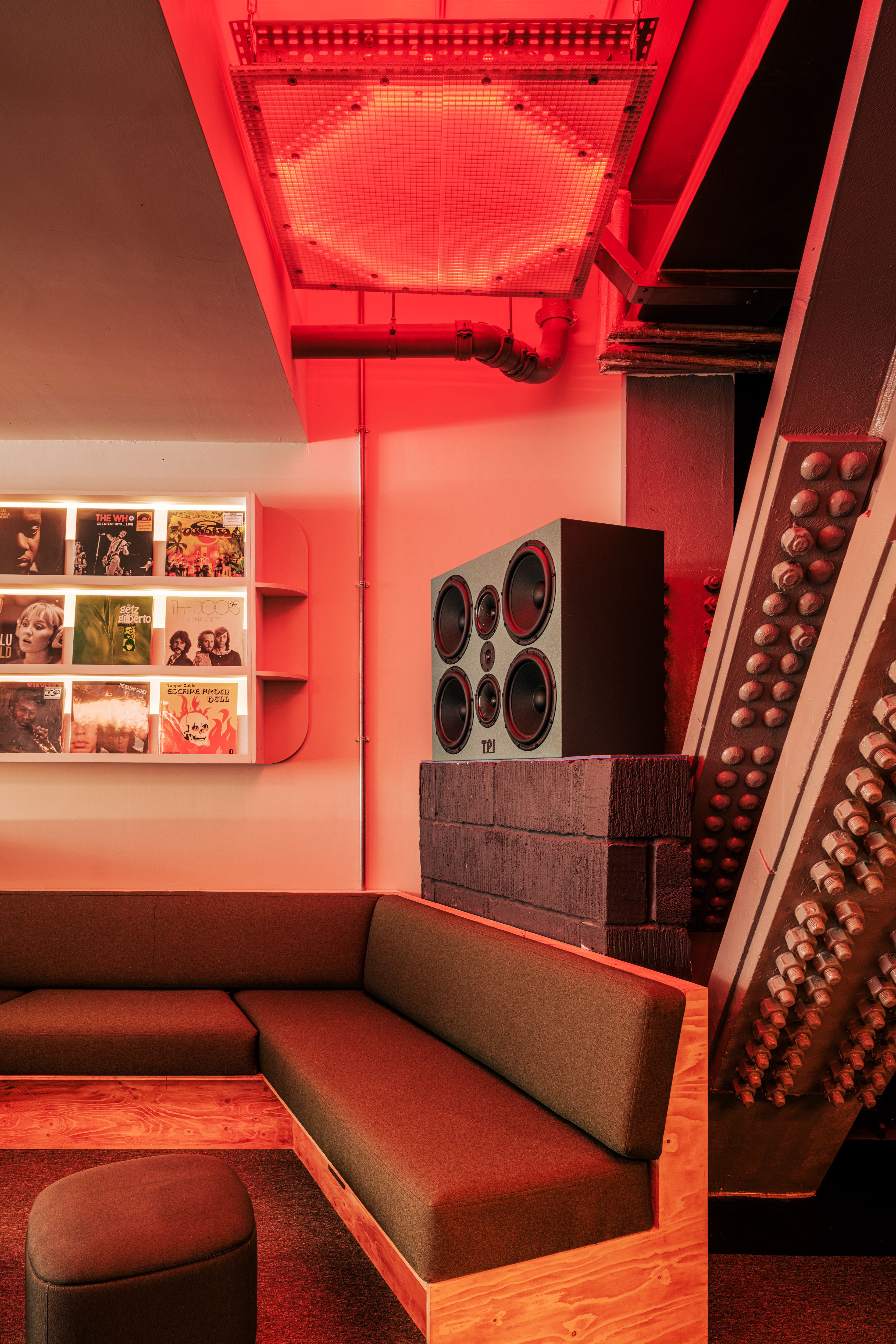 A red neon-lit listening bar packed with retro-fueled furnishings, geometrical lines, functional equipment, and an immersive vibe.