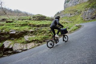 A 12-speed Brompton T-Line folding bike being ridden up a steep climb