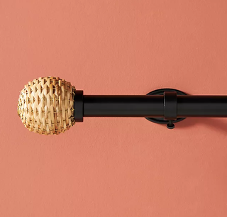 A black curtain rod with wicker end