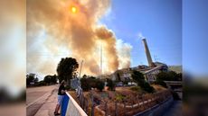 A man standing in front of the Kemerkoy Thermal Power Plant as wildfire approaches on Aug. 4, 2021.