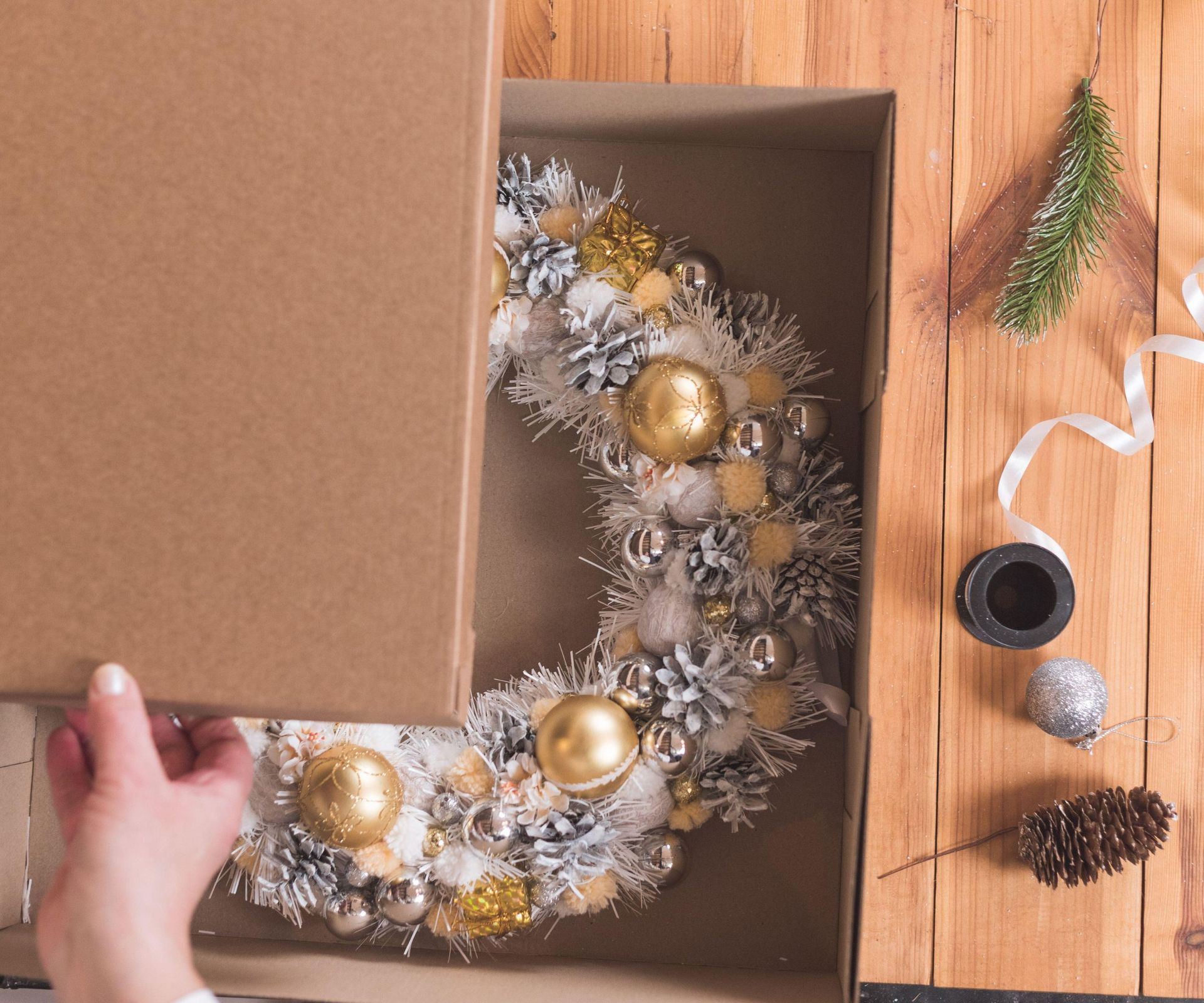 Someone packing a silver wreath into a square box