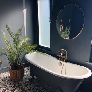deep blue bathroom with bathtub and plant pot