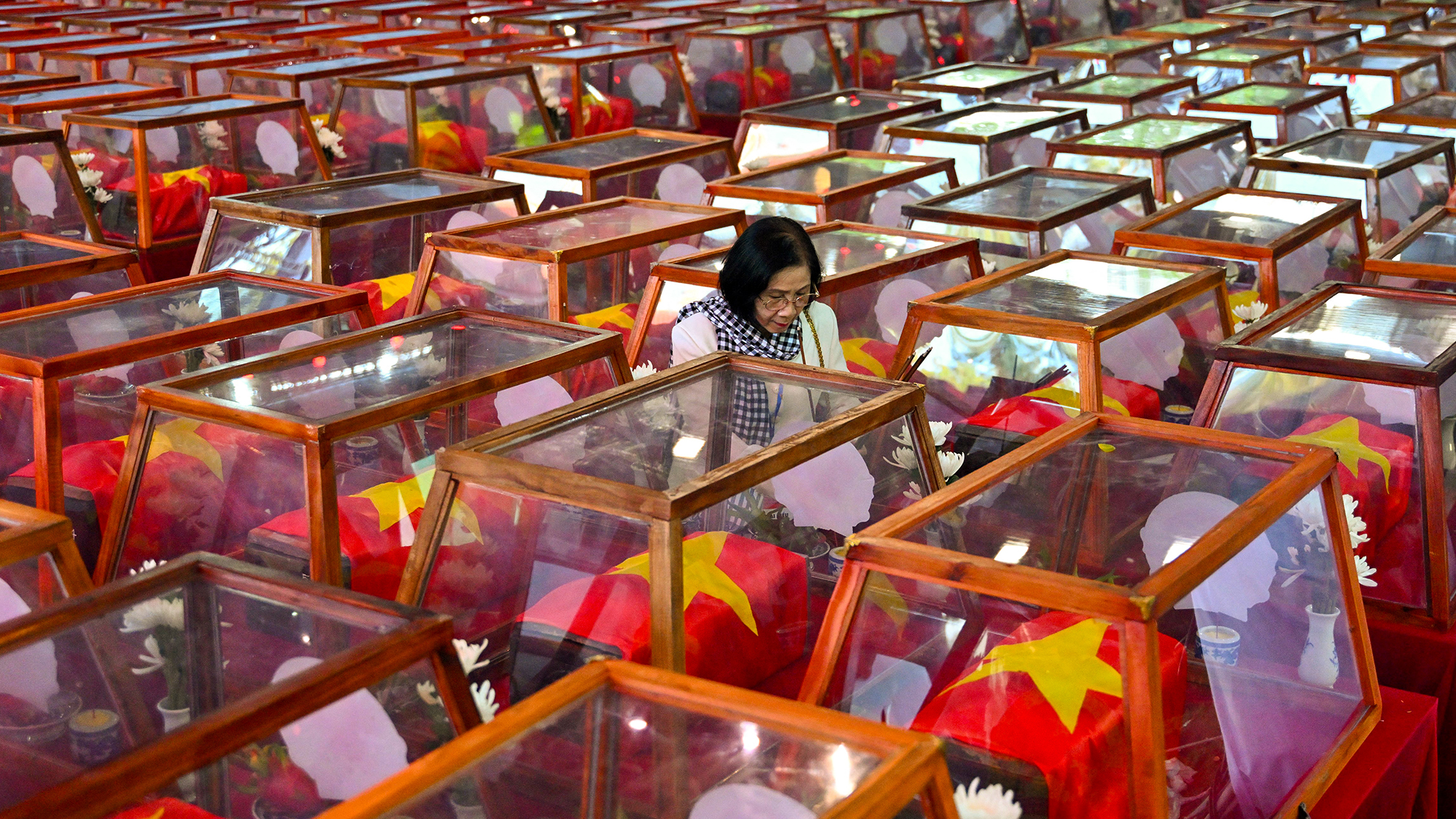 A woman stands beside caskets bearing the remains of fallen soldiers at L&amp;ecirc; Th&amp;#7883; Ri&amp;ecirc;ng Park in Ho Chi Minh City, Vietnam. Funeral rites for more than 700 war dead were held in an effort to identify those missing from decades of conflict
