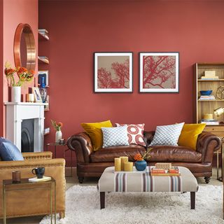 living area with red wall and brown leather sofa and arm chair