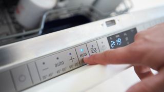finger selecting eco mode on dishwasher