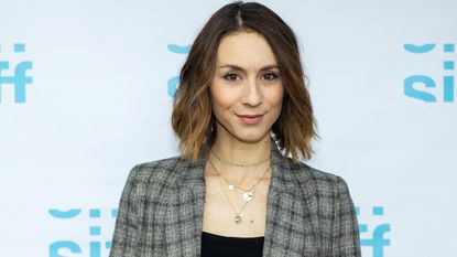 Troian Bellisario's living room is cozy and inviting. Here she is, a white woman with a brown bob, pictured in tweed blazer on red carpet