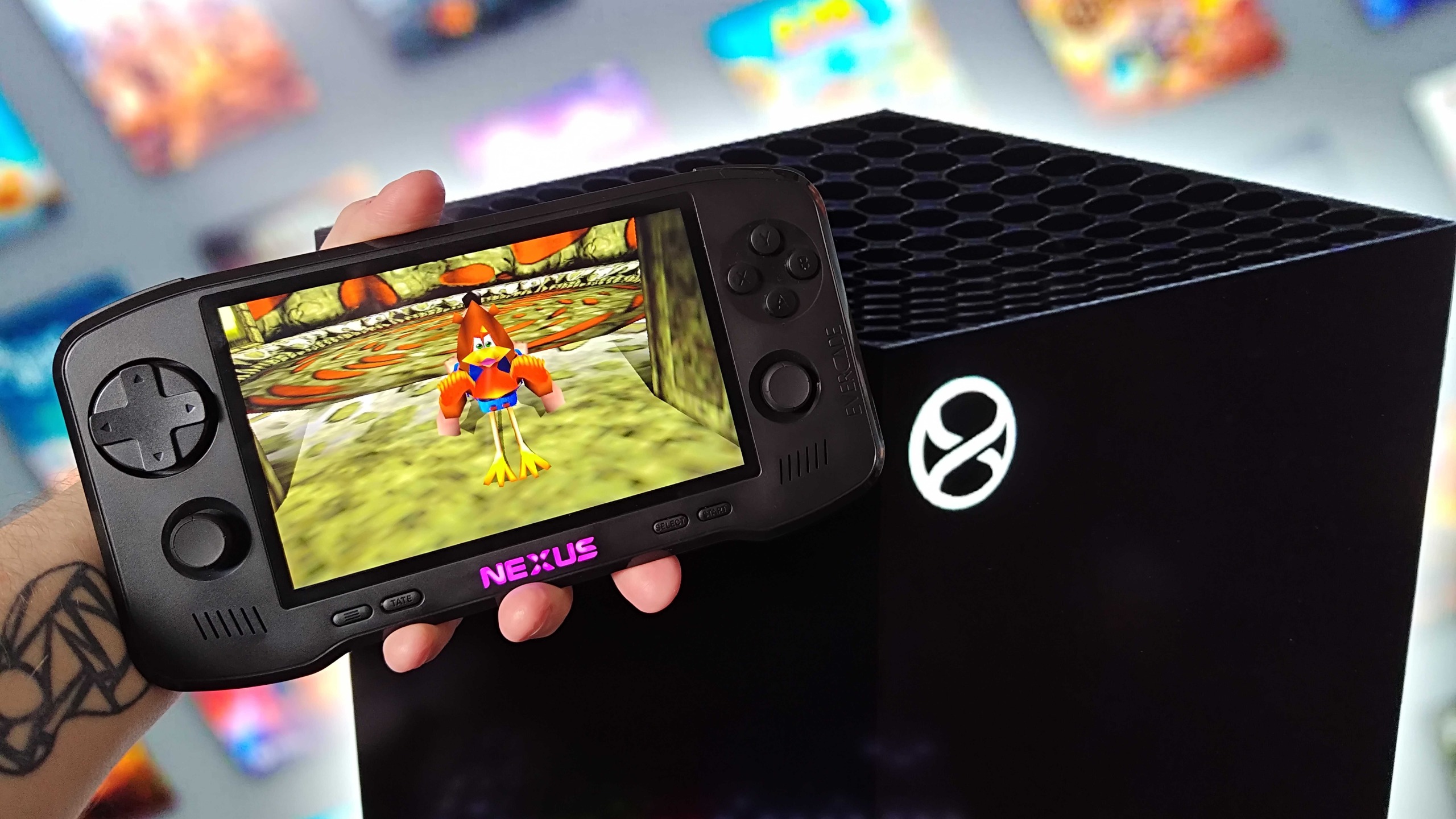 Hand holding Evercade Nexus next to a mockup of the next-gen Xbox Project Helix console with Banjo-Tooie gameplay on screen with Kazooie in trot mode.