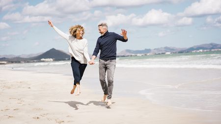 Cheerful mature couple having fun on shore at beach
