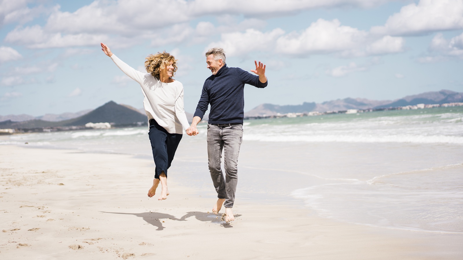 Cheerful mature couple having fun on shore at beach
