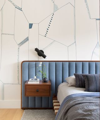 Bedroom with Japandi influences featuring a blue upholstered headboard, low bed, floating side tables, and geometric neutral wallpaper