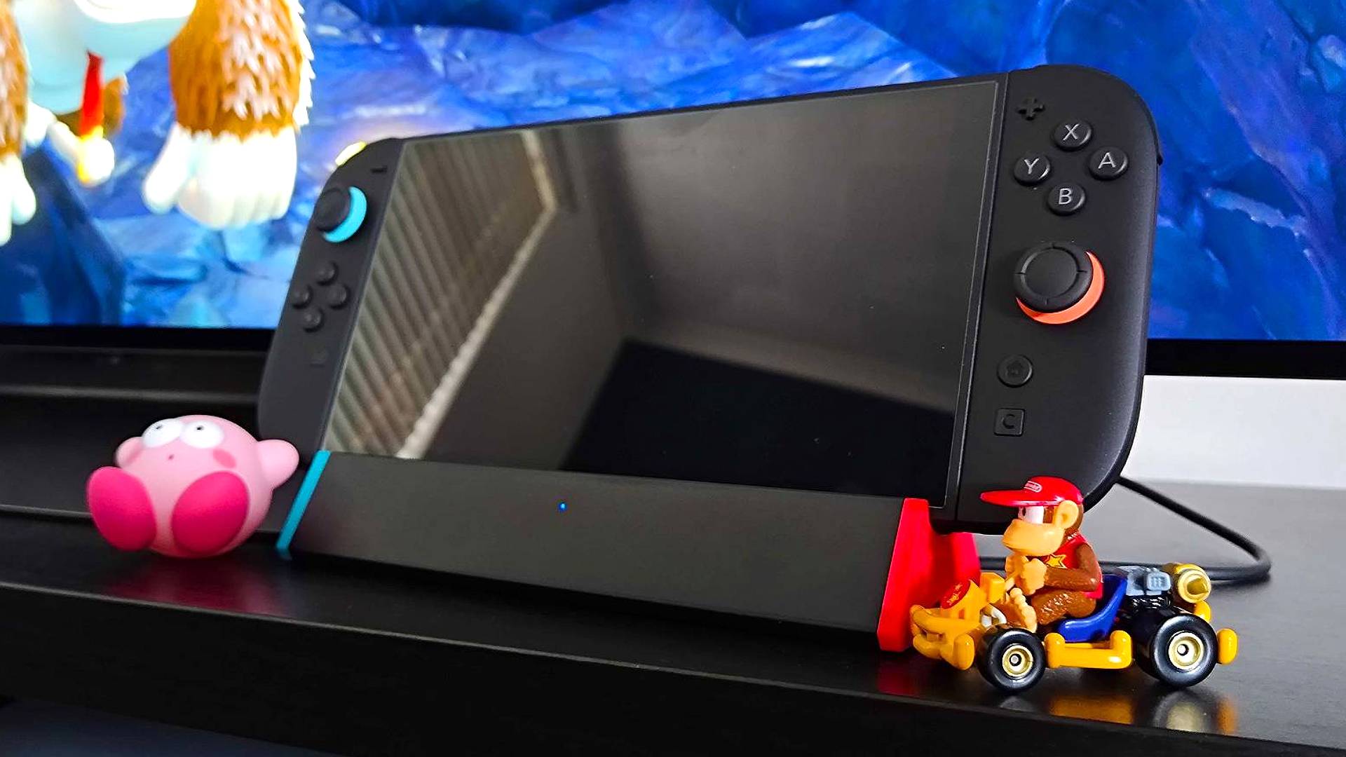SIWIQU Nintendo Switch 2 dock on TV bench with Kirby figure on left and Diddy Kong Mario Kart car on right.