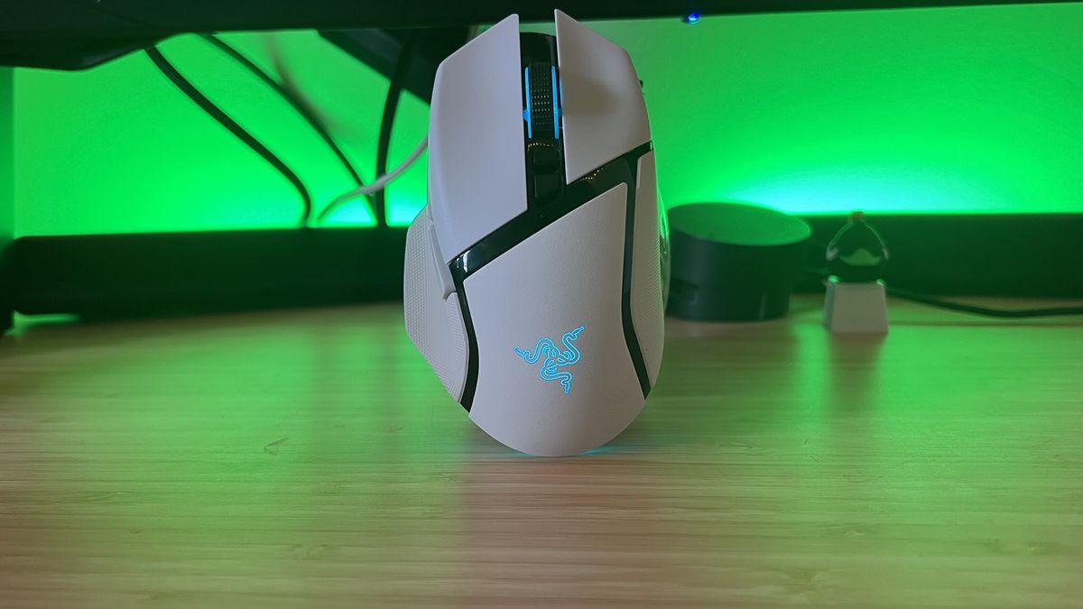 White Razer Basilisk V3 Pro 35K gaming mouse standing up against a green-lit setup