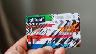 A hand holding a giffgaff SIM card
