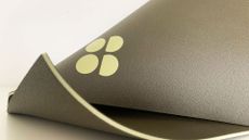 Image shows a half unrolled green Sweaty Betty Super Grip Yoga Mat.