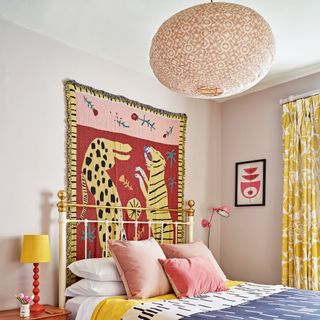 Pink bedroom with wall hanging and patterned ceiling lamp