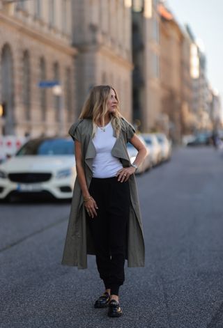 woman wearing white t-shirt, sweatpants, a baseball cap, and sneakers