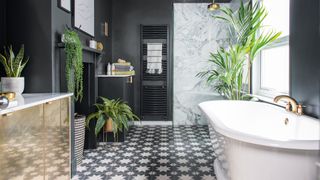 Black bathroom with marble shower and gold fittings with a key bathroom trend of a decorative fireplace