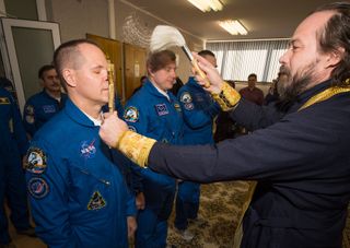 A priest offers the crew of Expedition 33/34 a traditional prelaunch blessing on Oct. 23, 2012.