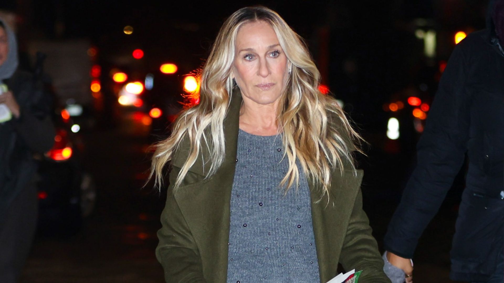 Sarah Jessica Parker walks down the street in New York wearing a polka dot skirt, grey jumper, green jacket and t-bar flats.