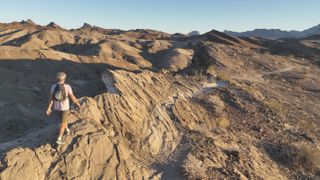 Aerial view as he follows trail through arid desert landscape