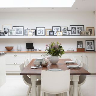 white dining room with dining table and wall shelf