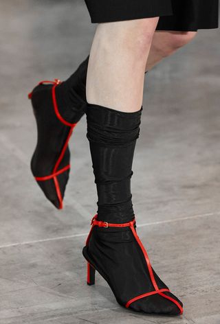 a close-up photo of a model walking in Jil Sander's spring show wearing one of the best strappy sandal trends: T-strap sandals
