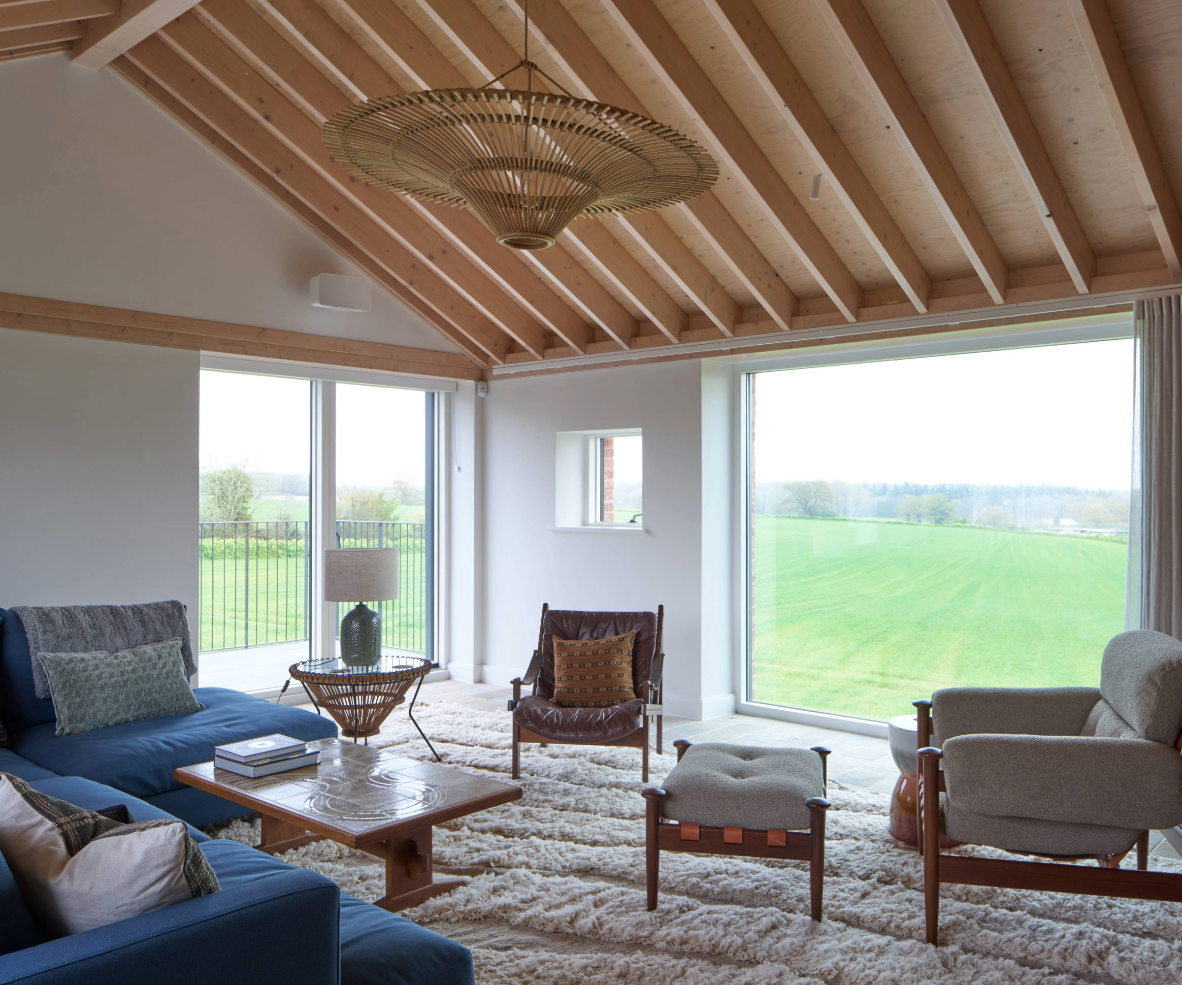 Living area with sofa, seats, vaulted ceiling and large windows
