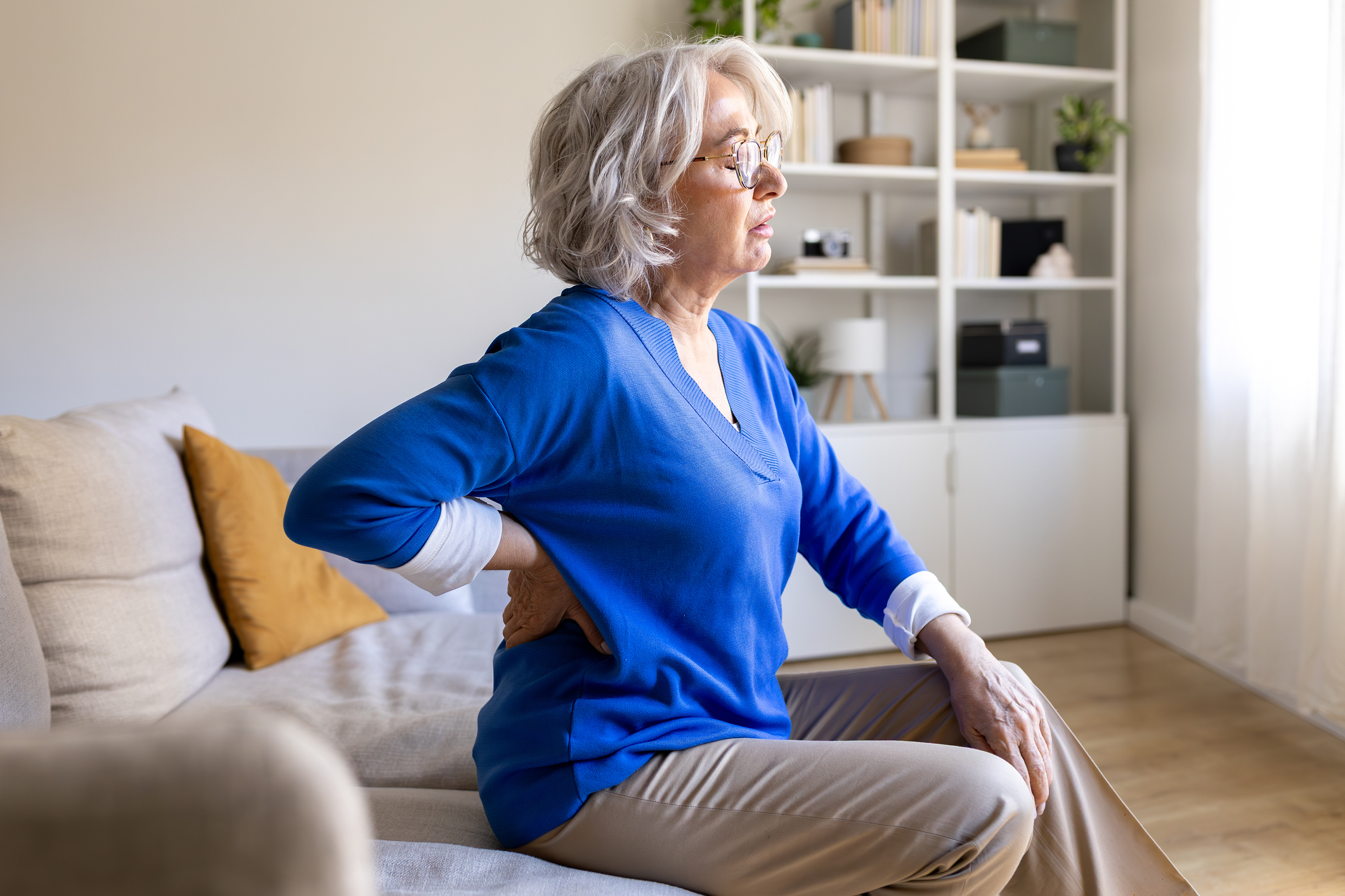 A woman with back pain, a common condition for Attendance Allowance claims