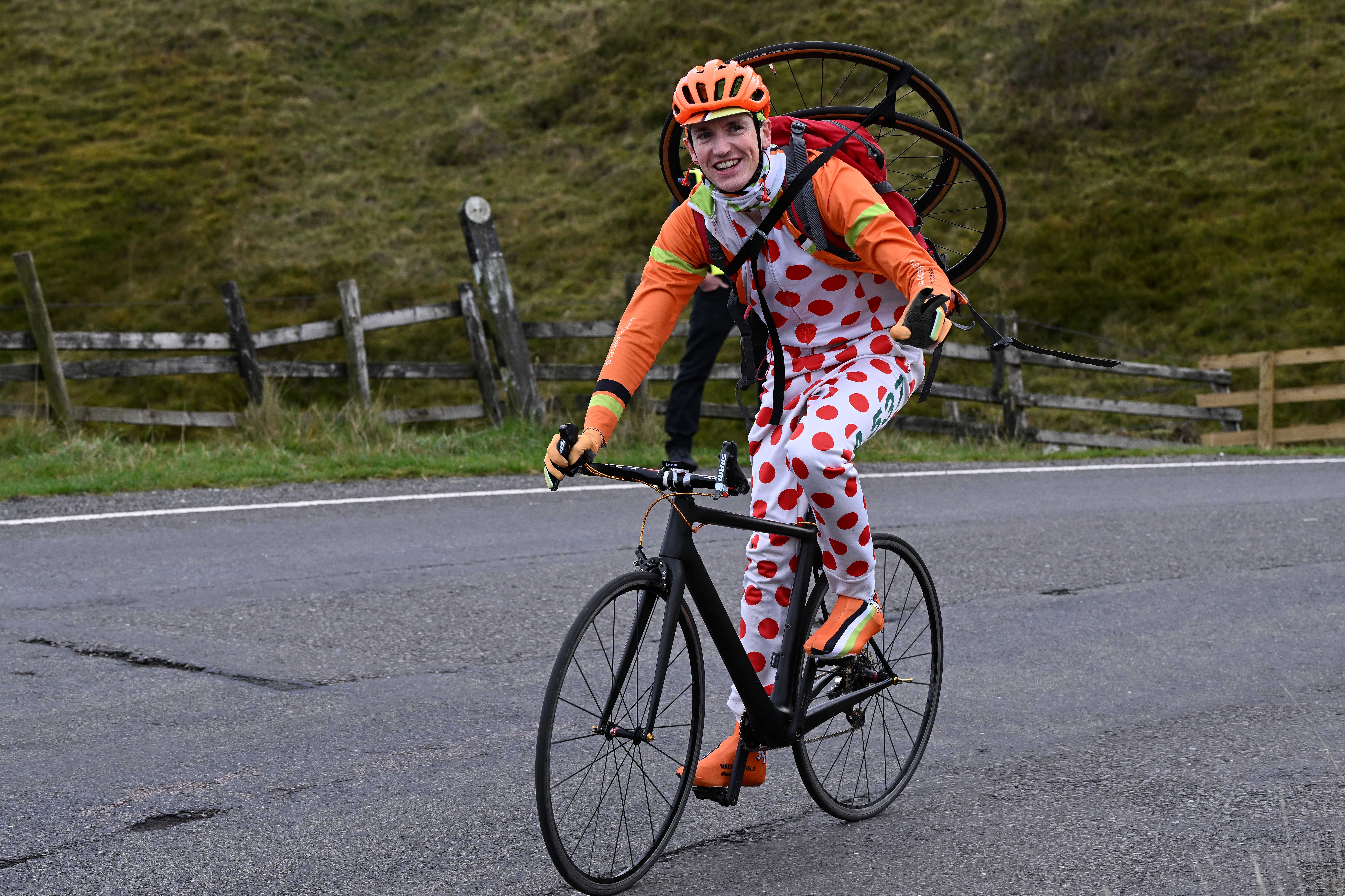 Man cycles uphill with tyres on his back