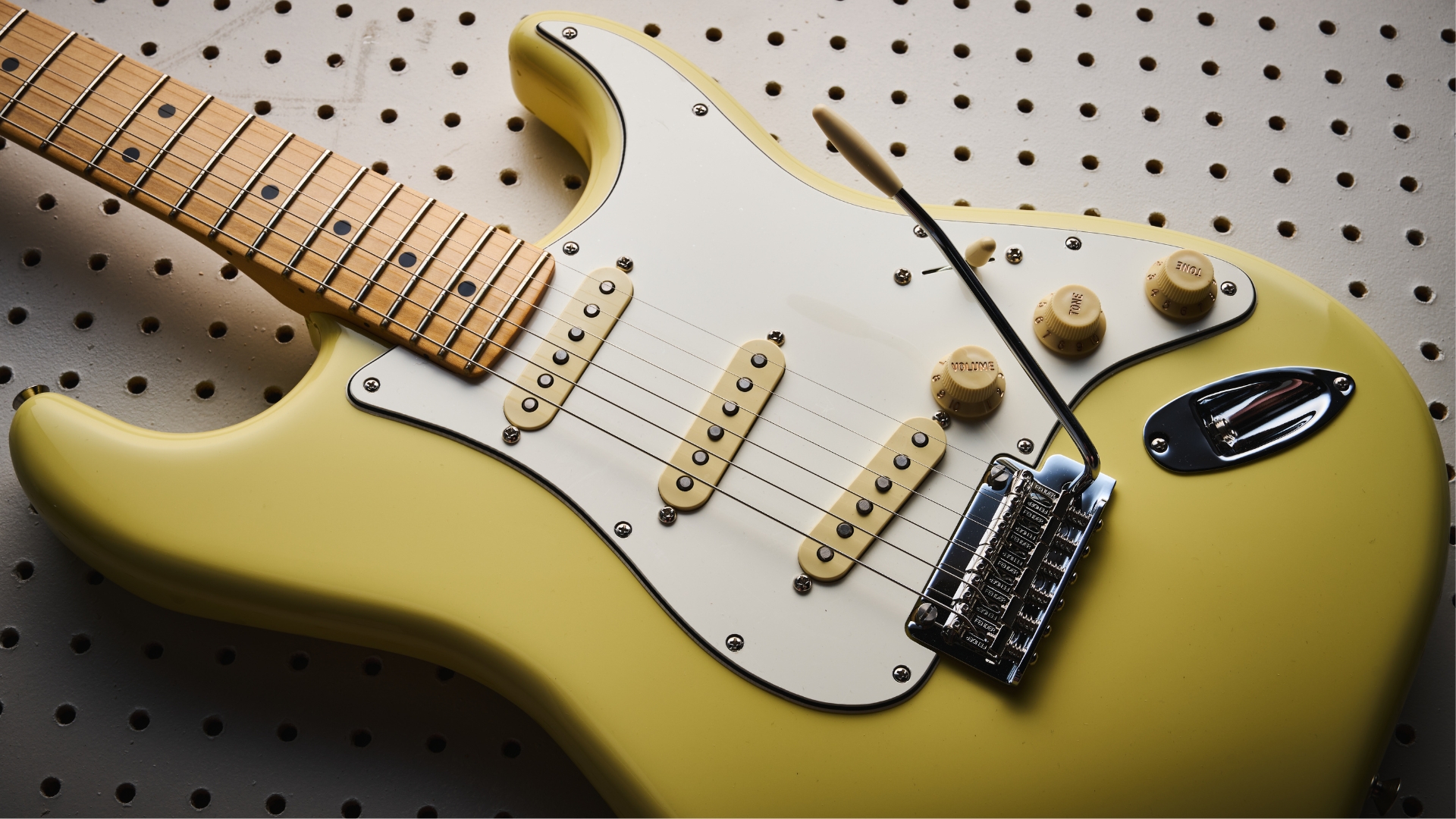 A Fender Player II Stratocaster lying on a white pegboard