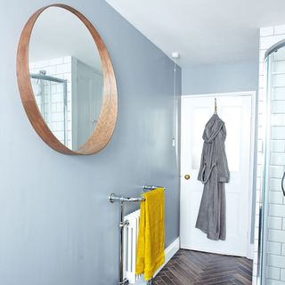 bathroom with blue wall round mirror and bathrobe on white door